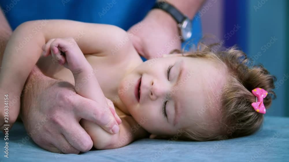 Medical centre. A doctor doing exercises with a little baby with cerebral palsy disorder. A baby looking at the doctor and smiling Medical centre. A doctor doing exercises with a little baby with cerebral palsy disorder. A baby looking at the doctor and smiling