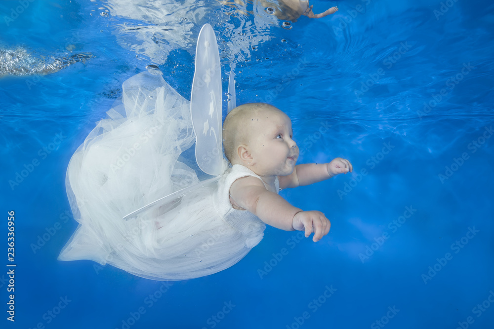Funny face portrait of little baby girl in the suit fairy swim underwater on a blue water ...