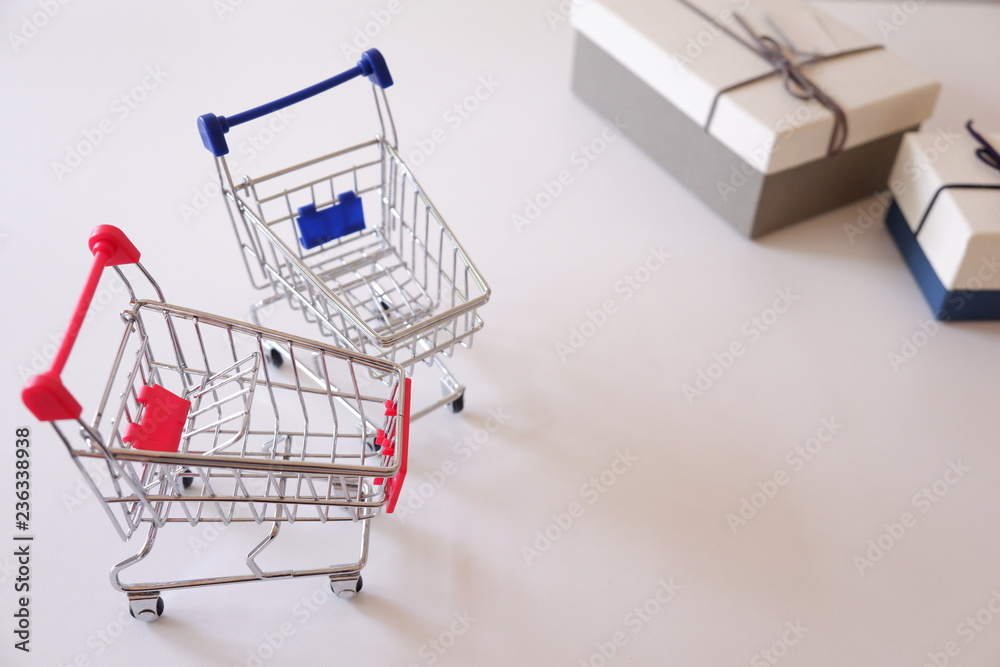Close-up of gift boxes and shopping cart  on white desk.