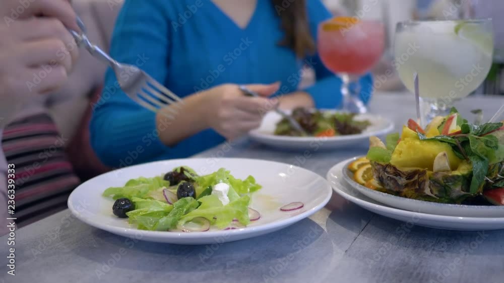 healthy lifestyle, girls on a diet eats greek salad from white plates sitting at the table in cafe healthy lifestyle, girls on a diet eats greek salad from white plates sitting at the table in cafe