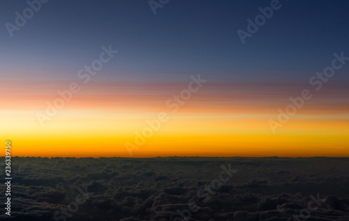 Colorful sunset over clouds. Orange and blue sky cloudscape views from airplane. Background texture  horizon concepts