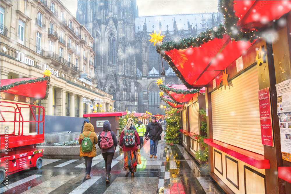 Naklejka premium Holiday cityscape - view of the Christmas Market (Weihnachtsmarkt) early morning on background the Cologne Cathedral, Germany, December, 2017