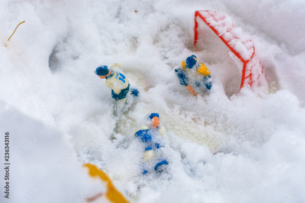 Children's board game of hockey was left in the open air in the yard and covered with the first snow. Toy hockey players under a snow.