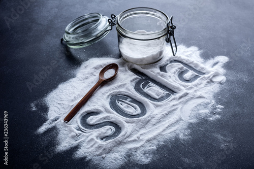 baking soda scattered from a glass jar on a dark background photo