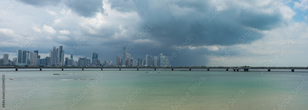 Hot humid day in Panama city as another rainstorm brews quickly over city skyline. Tall buildings shimmer in heatwaves rising in humid air. Hot humid day in Panama city as another rainstorm brews quickly over city skyline. Tall buildings shimmer in heatwaves rising in humid air.