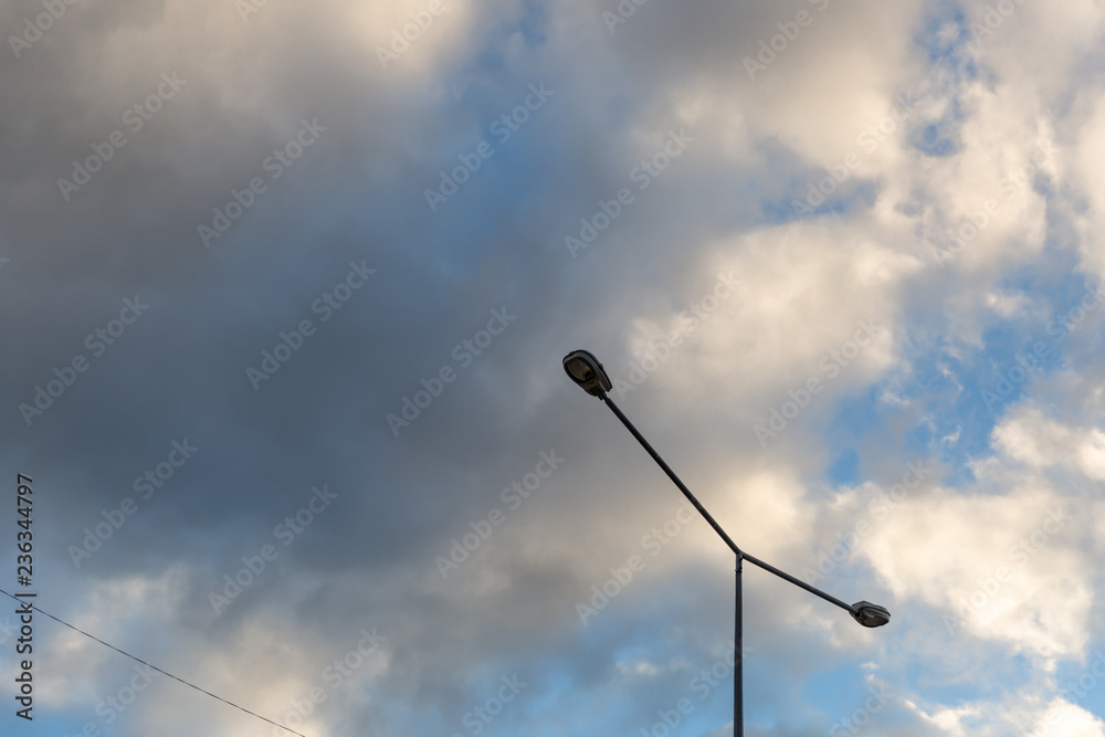 Street lamp against a background of sky and puffy clouds. Street light against blue sky and beautiful clouds. Street lamp against a background of sky and puffy clouds. Street light against blue sky and beautiful clouds.