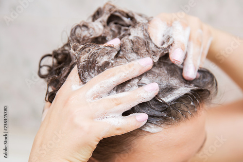 Young woman washing hair. Shampoo and foam on black woman's hair.