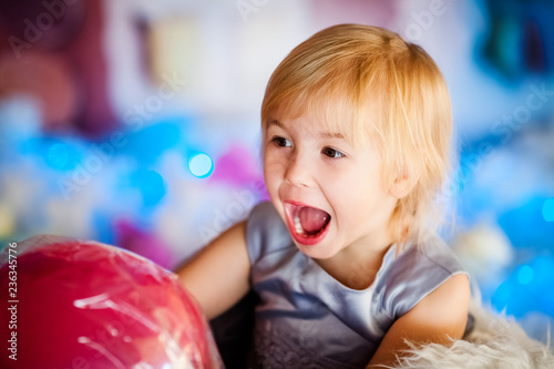 Portrait of little blonde smiling girl playing with toy candy. Christmas and New Year theme