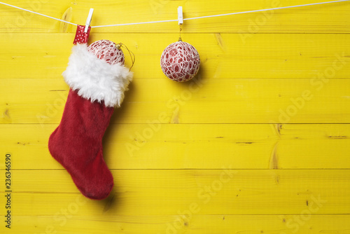 Red Santa stocking with Christmas decoration over yellow wooden background. photo