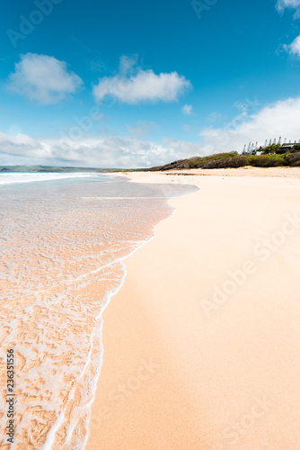 Perfect Day in Molokai Hawaii with Beautiful Island Paradise of Clear Aqua Blue Ocean Waves Coming on Sandy Golden Seashore and White Sand Beach and Rock Cliffs