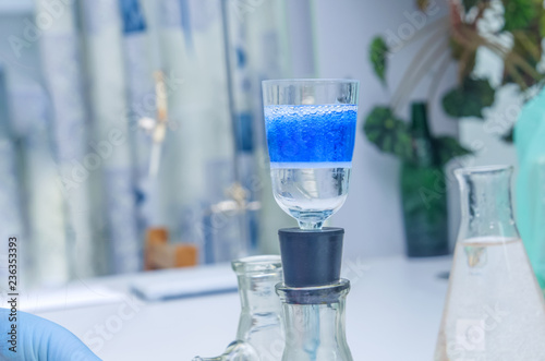 a chemist holds a glass test tube in his hand, overflows a liquid solution, conducts an analysis reaction using various reagent options using chemical production.