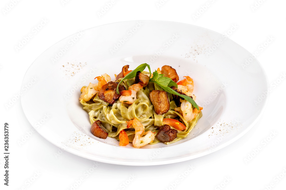 Plate of tasty seafood tagliatelle pasta with salmon and shrimps isolated at white background.
