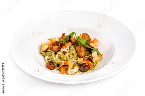 Plate of tasty seafood tagliatelle pasta with salmon and shrimps isolated at white background.