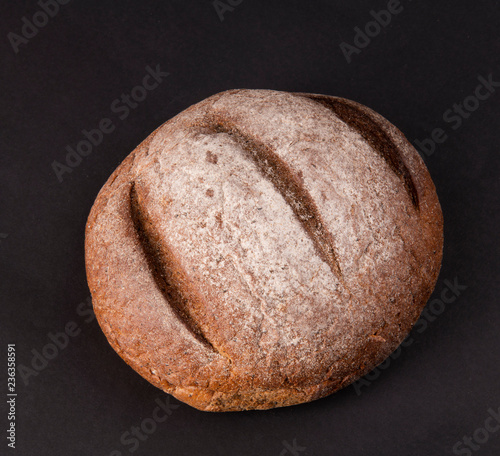 Булка черного хлеба на черном фоне