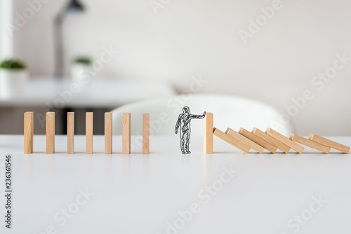 Hand drawn shape of businessman stopping domino effect photo