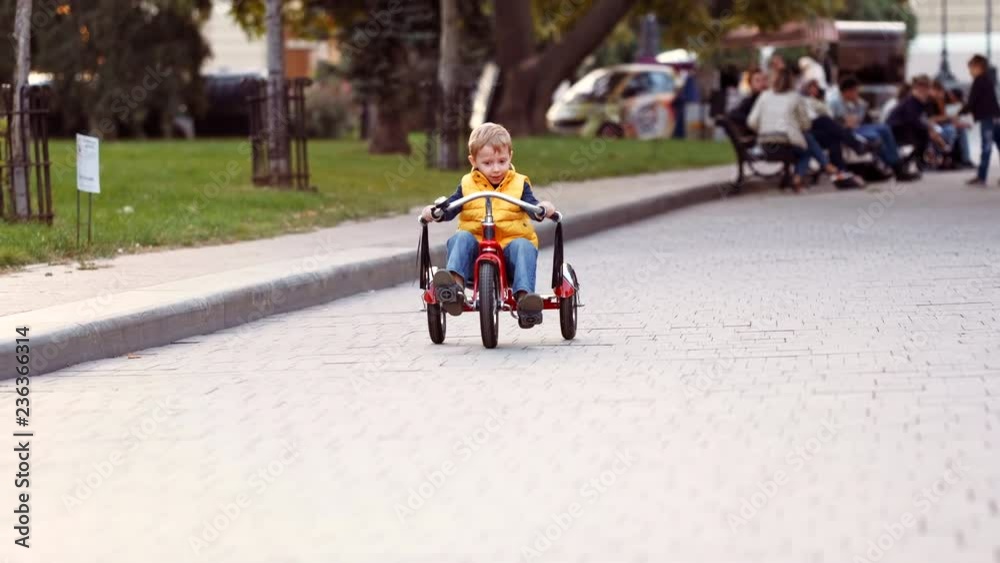 Happy child on red bike having fun outdoors. Active kid boy riding retro stylish bicycle. Cute smiling little boy playing and cycling on street road and spending family time. Slow motion video. Happy child on red bike having fun outdoors. Active kid boy riding retro stylish bicycle. Cute smiling little boy playing and cycling on street road and spending family time. Slow motion video.