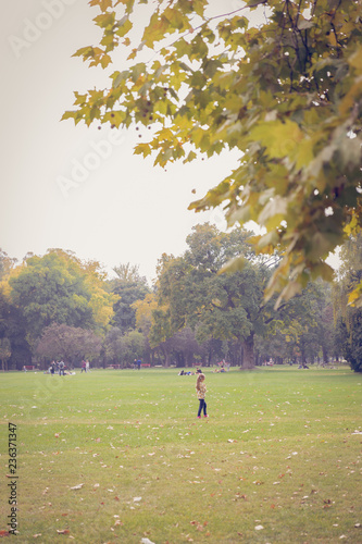 A young girl standing alone in the park. An autumn Sunday view at a public park © Elif