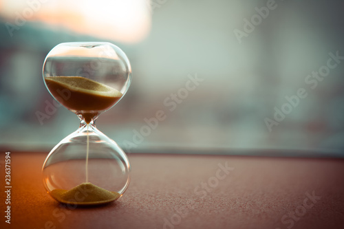 Sand running through the bulbs of an hourglass measuring the passing time in a countdown to a deadline, on a blur background with copy space photo