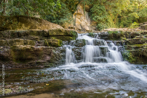 Fototapeta Naklejka Na Ścianę i Meble -  Beautiful stream waterfalls cascade over pretty green moss covered stones