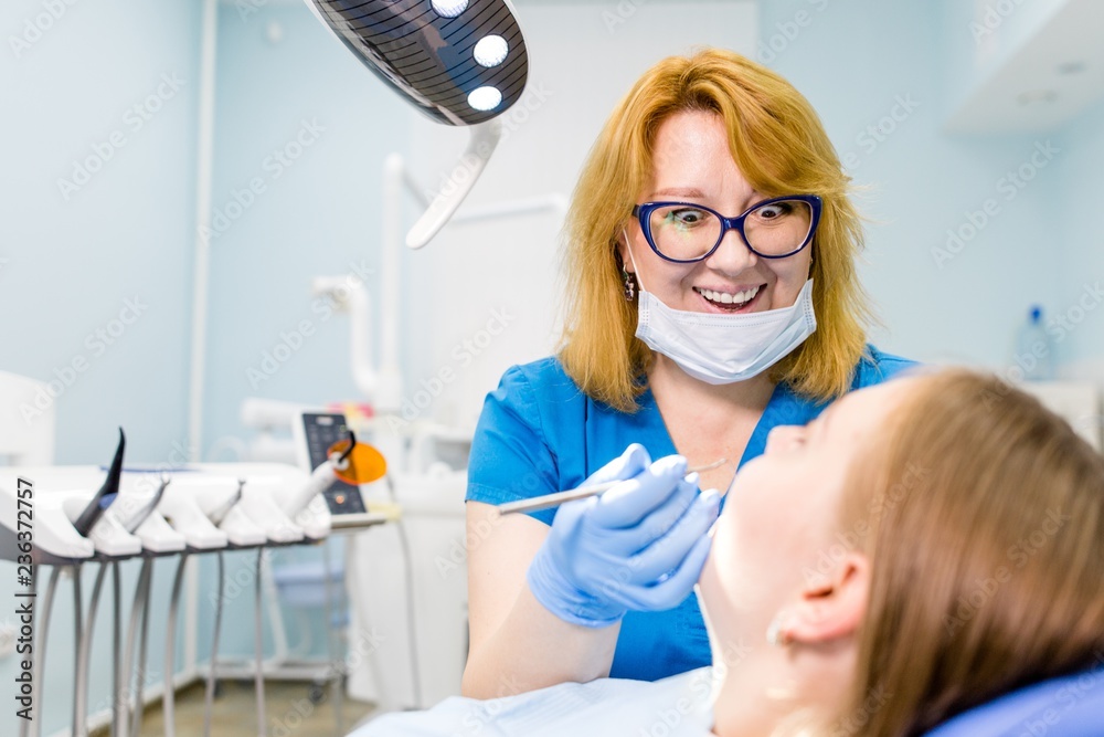 Dentist therapist checks the oral cavity of the client in the dental clinic