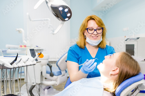 Dentist therapist treats a girl s teeth in a dental clinic
