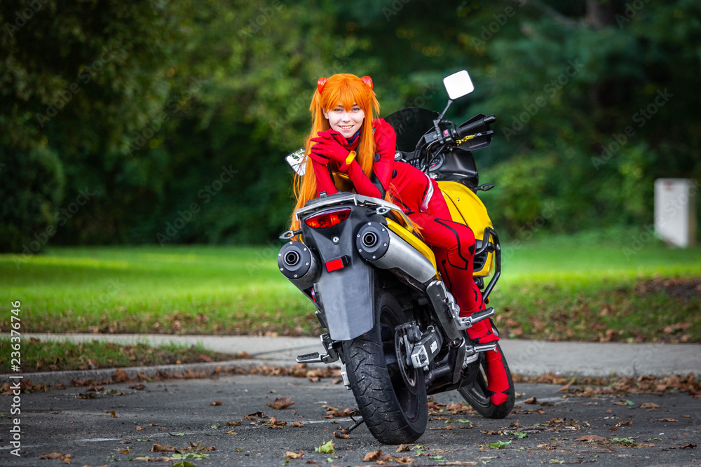 Obraz premium Young attractive girl in red posing with big motorcycle