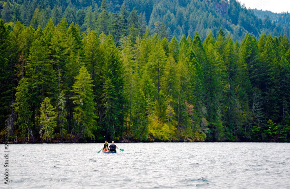 Man with girl and dog sail on boat along the picturesque mountain lake of Merwin with forest of green beaches