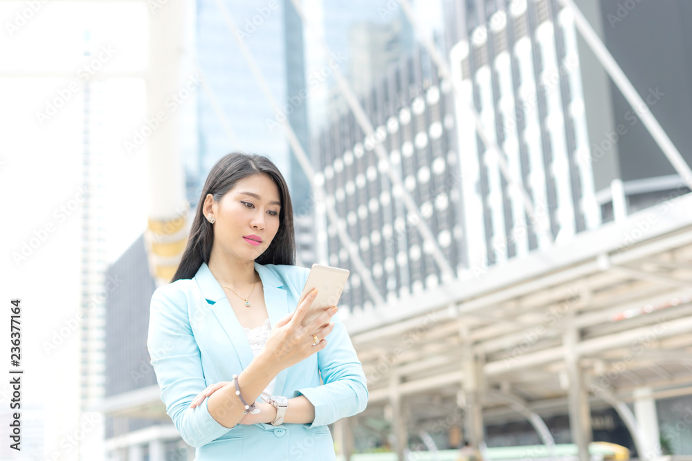 Beautiful cute girl in business woman clothes using smart phone computer , urban city background , business concept Beautiful cute girl in business woman clothes using smart phone computer , urban city background , business concept