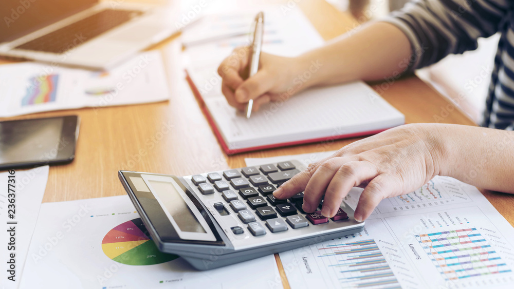 close up hand of business employee accountant with calculator calculating annual income tax and company income calculation - business concept close up hand of business employee accountant with calculator calculating annual income tax and company income calculation - business concept
