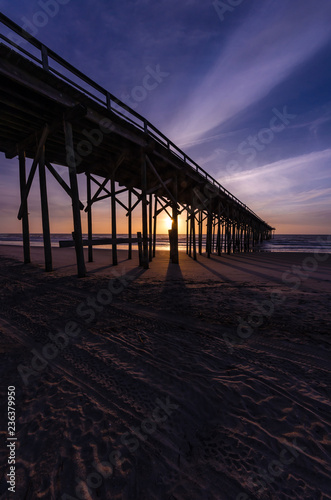 Rays of light at sunset behind a pier at Carolina Beach  North Carolina  USA