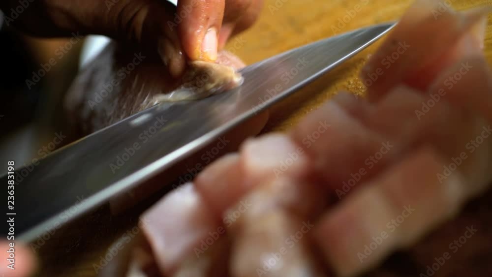 Balinese Chef cutting up uncooked local Mahi Mahi fish on wooden chopping board with knife 