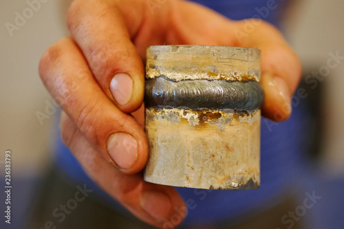 Metal pipe with a welded seam In the hand of a welder's man. photo