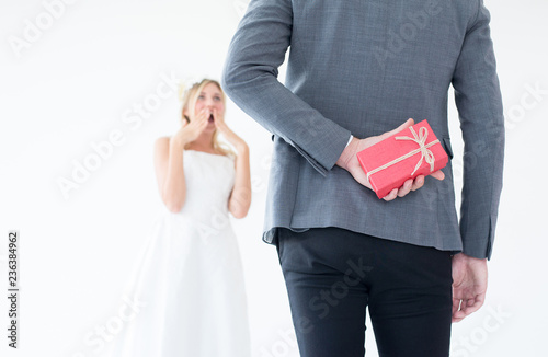 Groom hiding red gift box behind back in order to surprise bride on the wedding day,Woman positive emotion and face astonished happy and smling