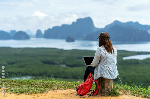 Fotografia Back side of Asian woman freelancer working with technology laptop with happines