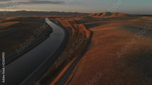 Aerial of gorgeous twilight in California.  The heart of an agricultural water dispute.  A life giving canal is visible below, as are beautiful mountains in this stunning sunset view of the foothills. photo