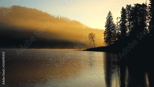 Foggy morning near Jonsvatnet lake. Misty air and flowing fog above calm surface of the lake. Norwegian autumn time. photo