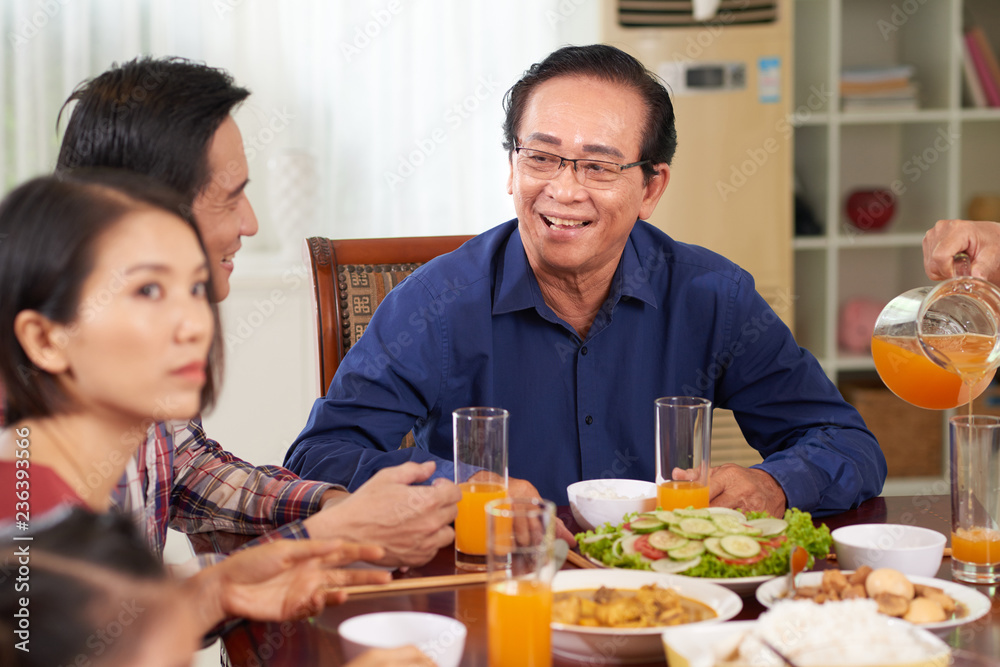 Senior Vietnamese man enjoying dinner with his family Senior Vietnamese man enjoying dinner with his family
