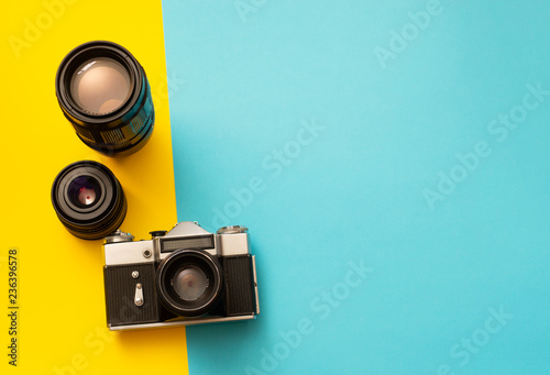 Photo camera with spare lenses on blue and yellow background