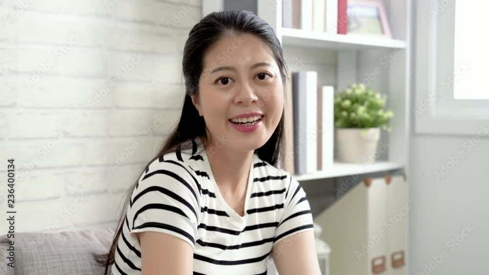 attractive asian lady turning face to camera cheerfully smiling. young beautiful girl wearing t shirt laughing enjoy spending time alone at home. lazy woman resting sitting on couch in living room. attractive asian lady turning face to camera cheerfully smiling. young beautiful girl wearing t shirt laughing enjoy spending time alone at home. lazy woman resting sitting on couch in living room.