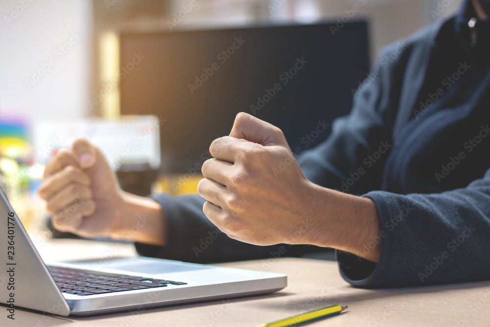 Close-up Business man with raised fists sitting at her desk. Celebrating Success . Close-up Business man with raised fists sitting at her desk. Celebrating Success .