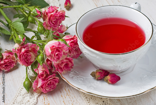 Cup of tea with dried rose buds and fresh roses