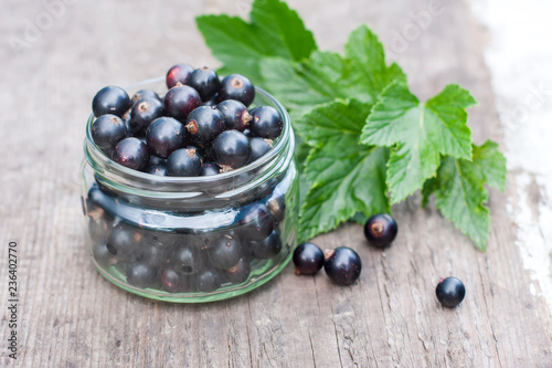 fresh black currant in the glass, on rustic wooden board.