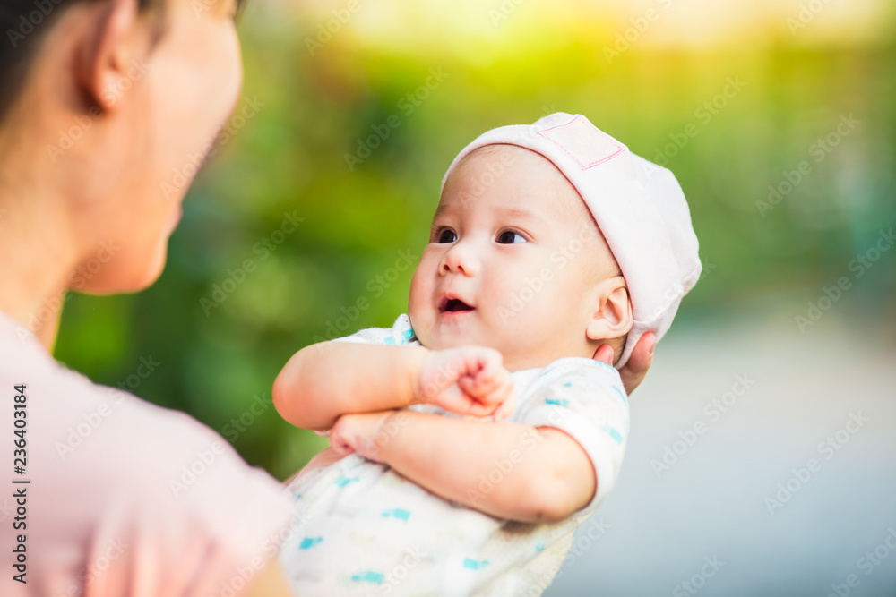 3 months baby feeling happy and smiles with her mother in the garden.Portrait of Asian family. 3 months baby feeling happy and smiles with her mother in the garden.Portrait of Asian family.