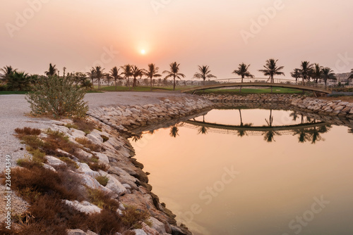 September 16, 2017 - Al Hamra Village in Ras al Khaimah, United Arab Emirates. Embankment, palms, bridge and golf course with apartment buildings by arabian sunrise.