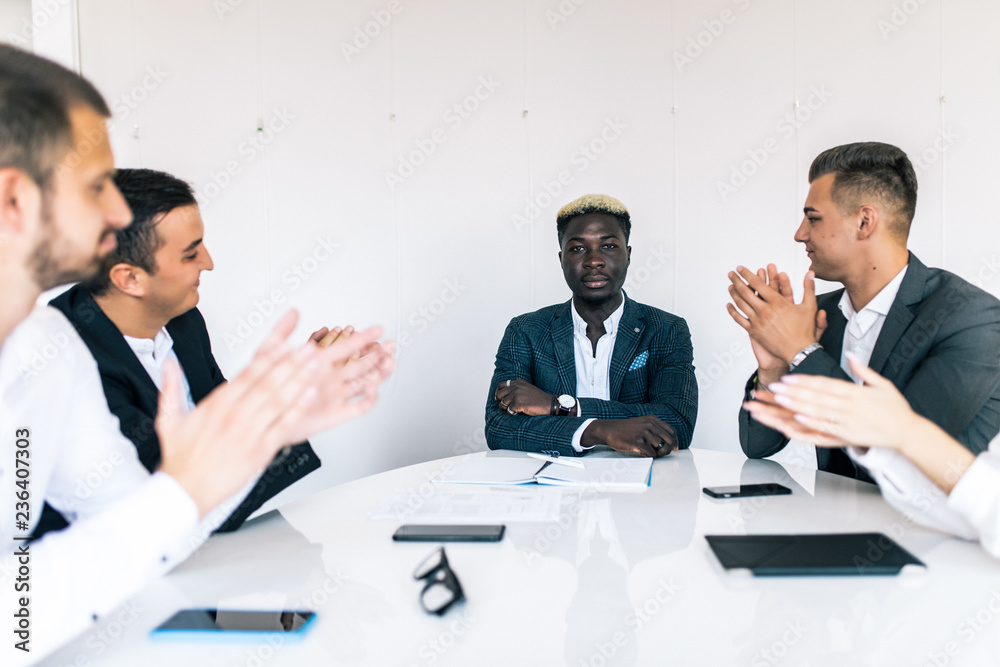Great presentation. Group of happy business people in smart casual wear sitting together at the table and applauding to leader Great presentation. Group of happy business people in smart casual wear sitting together at the table and applauding to leader