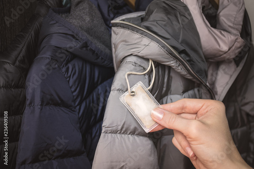 Female hand holding a small transparent plastic bag with winter jacket's filling (down) sample. Choosing qualitative filling for winter clothes.