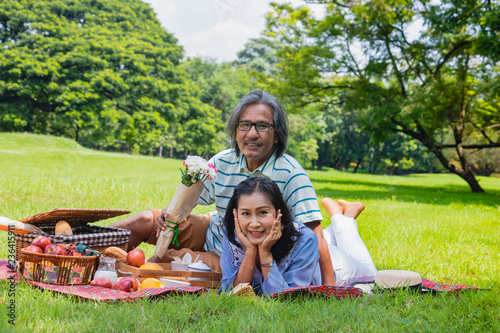 The old couple relax in park. In the morning Man hugging woman beside picnic basket.They are in love and sweet.Life style, Exercise ,Photo concept  love and healthy. © Teerayut