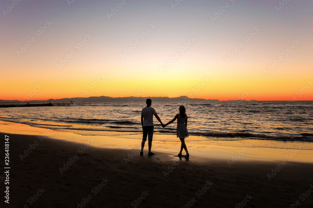 Young couple by the sea watching the sunset