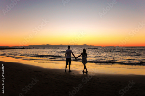 Young couple by the sea watching the sunset