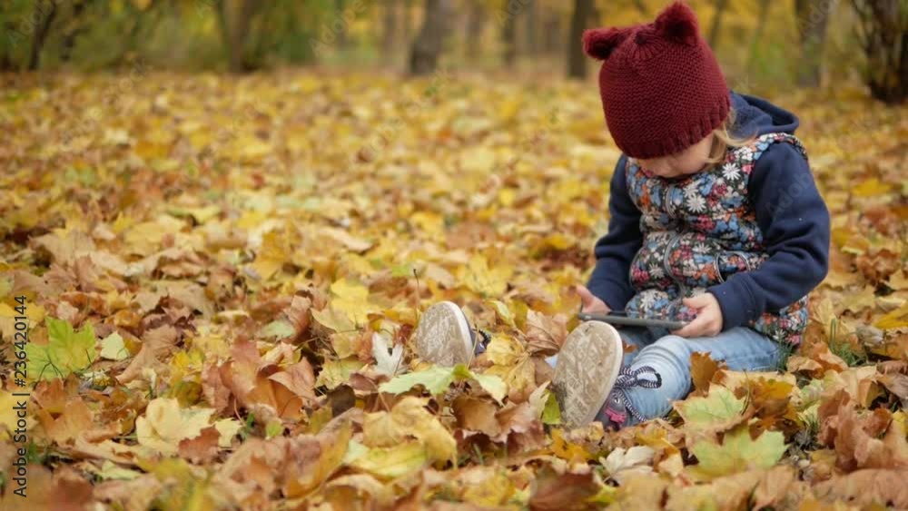 Girl sitting in the autumn yellow leaves with the phone Girl sitting in the autumn yellow leaves with the phone